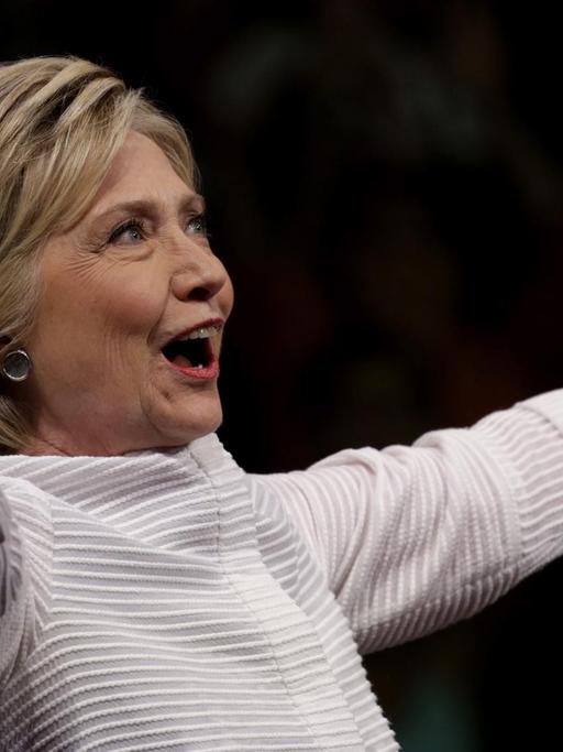 Hillary Clinton breitet die Arme weit aus.