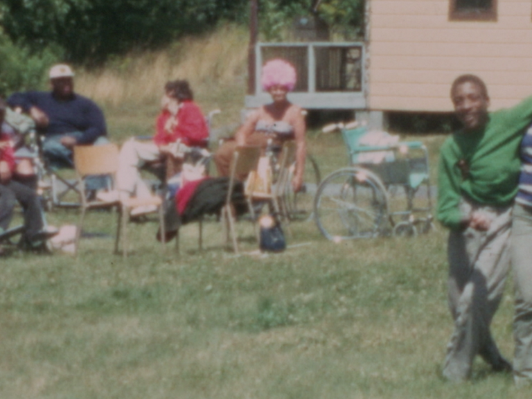 Jugendliche auf einer Wiese, manche sitzen in einem Rollstuhl.