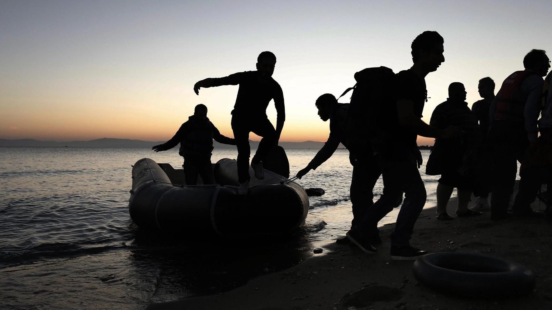Flüchtlinge entsteigen einem Schlauchboot und gehen an Land. Flüchtlinge entsteigen einem Schlauchboot und gehen an Land.