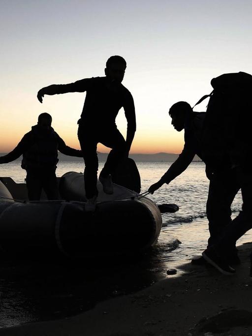 Flüchtlinge entsteigen einem Schlauchboot und gehen an Land.