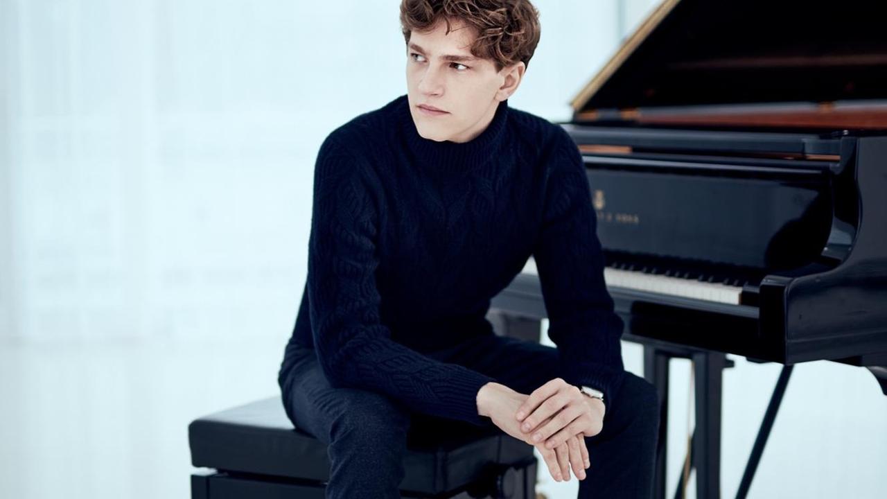 Der Pianist sitzt vor einem aufgeklappten Flügel Der Pianist sitzt vor einem aufgeklappten Flügel