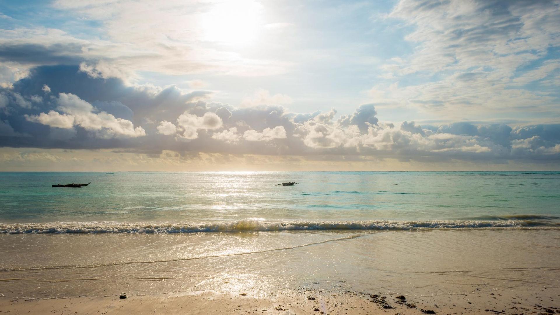 Die Sonne steht über dem Wasser und einem Strand. Die Sonne steht über dem Wasser und einem Strand.