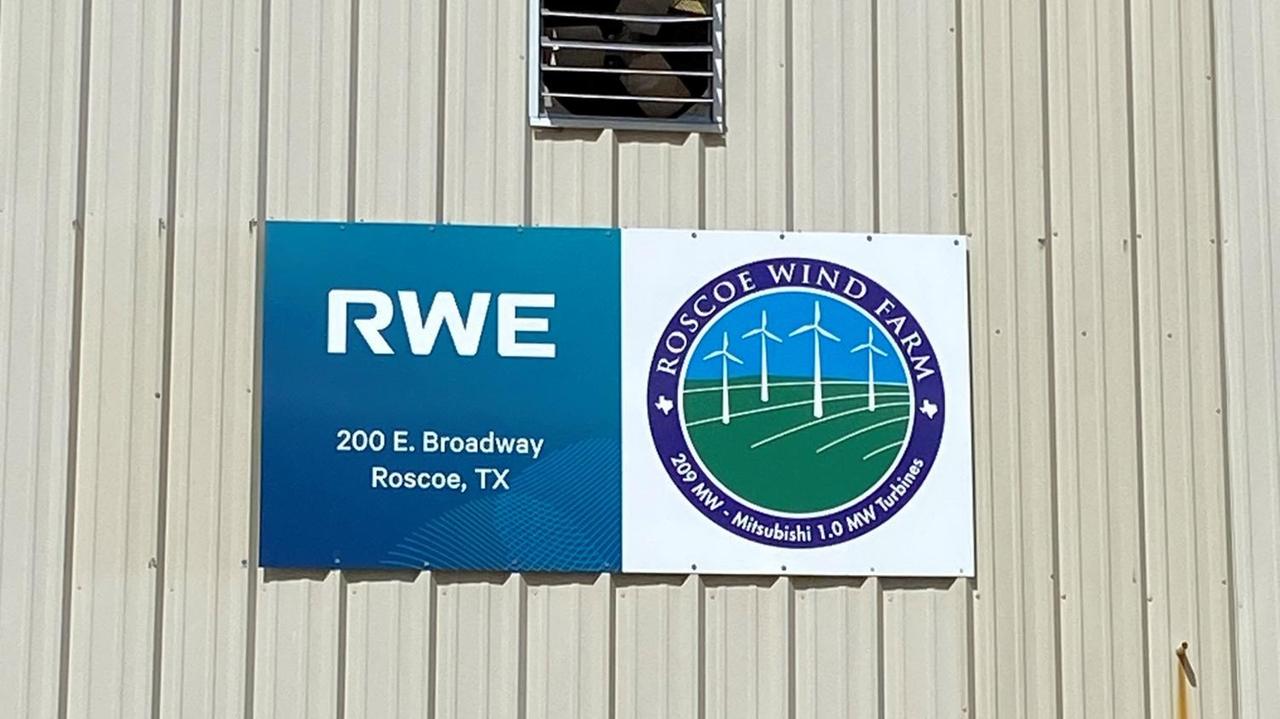 An einer weißen Holzhütte sind zwei Schilder befestigt. Auf einem steht RWE. An einer weißen Holzhütte sind zwei Schilder befestigt. Auf einem steht RWE.