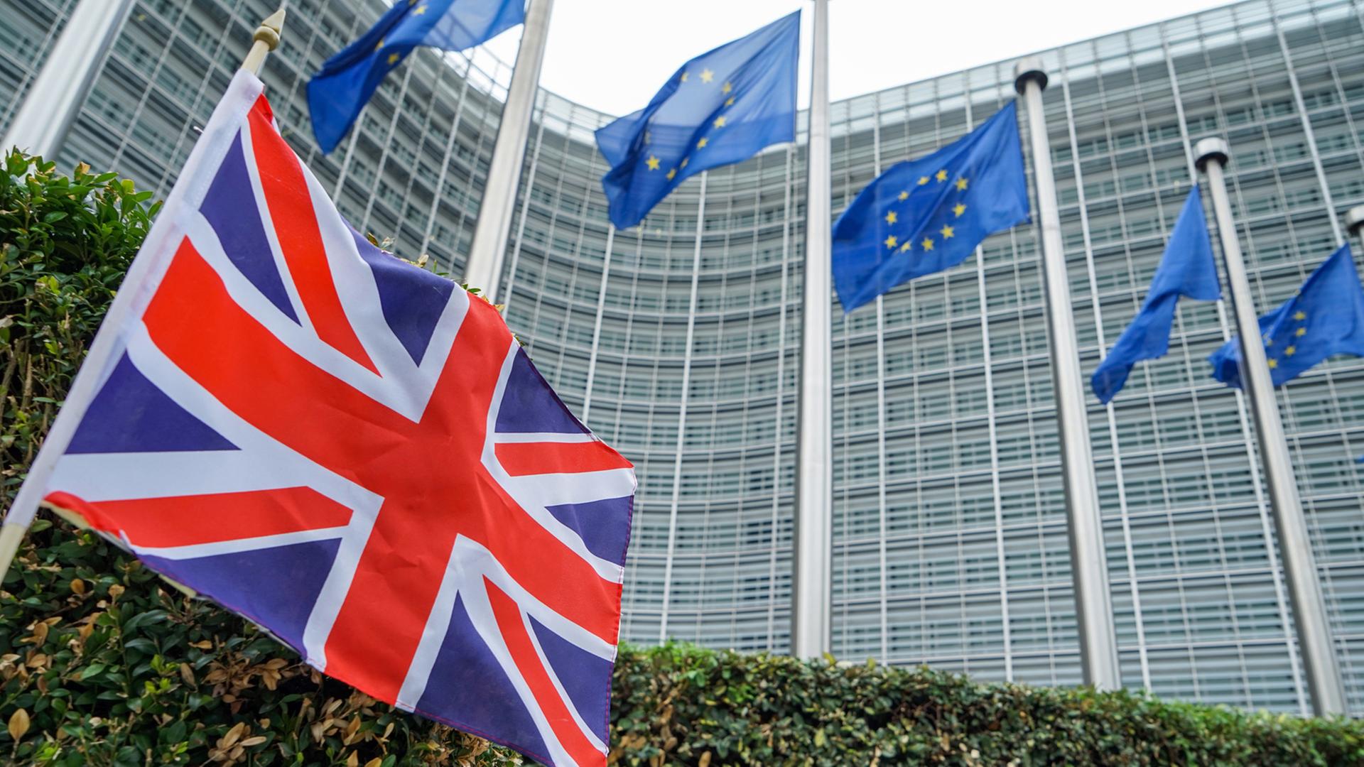 Fahne der EU vor der Europäischen Kommission in Brüssel und eine kleine Fahne Großbritanniens Fahne der EU vor der Europäischen Kommission in Brüssel und eine kleine Fahne Großbritanniens