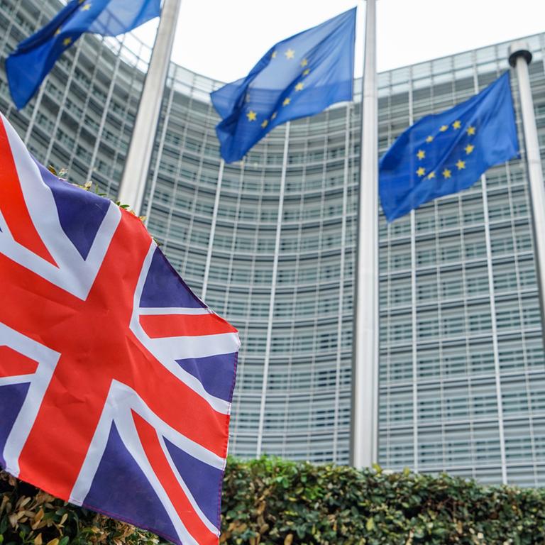Fahne der EU vor der Europäischen Kommission in Brüssel und eine kleine Fahne Großbritanniens