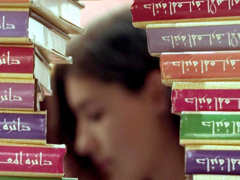 Hinter einer islamischen Enzyklopädie liest eine Besucherin auf der Frankfurter Buchmesse 2004 in der Halle der "Arabischen Welt".