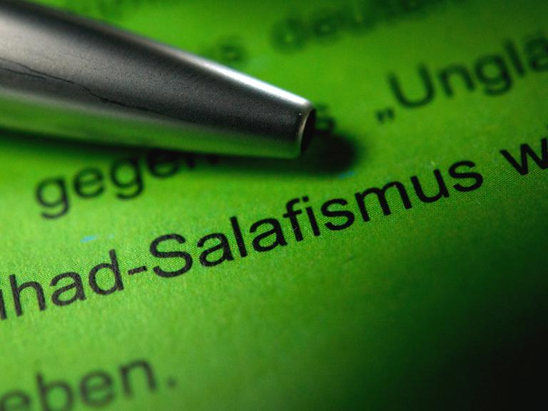 Ein Kugelschreiber zeigt auf einen Text, in dem die Worte "Jihad-Salafismus" zu lesen sind.
