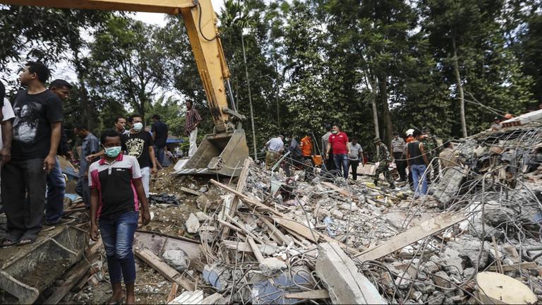 Petugas penyelamat mencari korban selamat dari puing-puing di BT Jaya kabupaten Aceh setelah gempa.