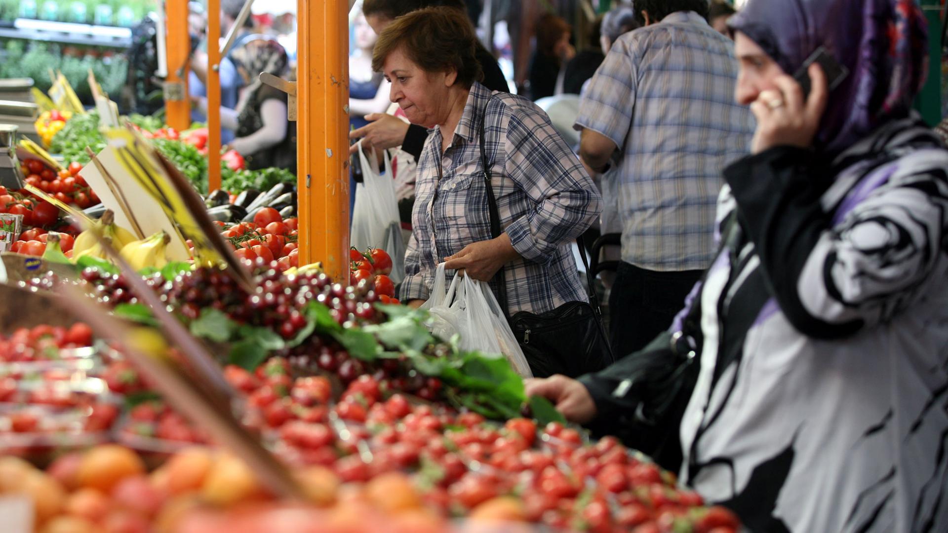 Besucher kaufen in Berlin an einen Marktstand auf dem Maybachufer-Wochenmarkt "Bioriental" Obst und Gemüse. Besucher kaufen in Berlin an einen Marktstand auf dem Maybachufer-Wochenmarkt "Bioriental" Obst und Gemüse.