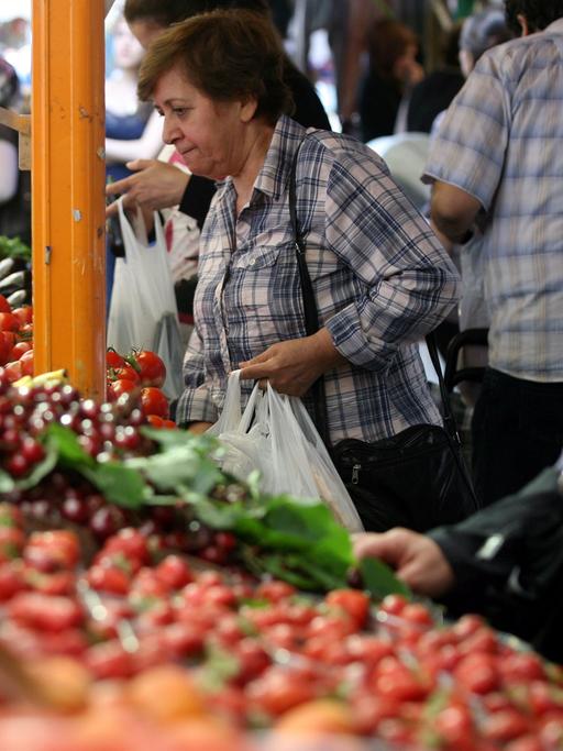 Besucher kaufen in Berlin an einen Marktstand auf dem Maybachufer-Wochenmarkt "Bioriental" Obst und Gemüse.