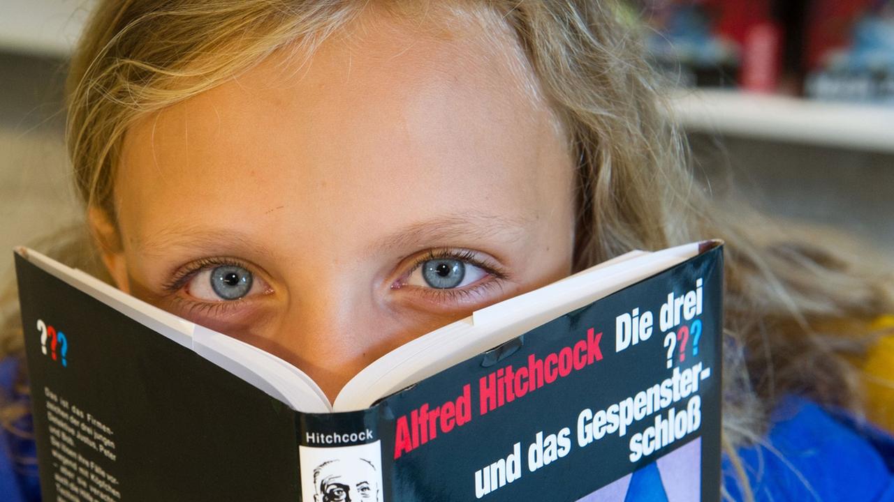 Ein Kind mit einem Buch aus der Reihe "Die drei ???" Ein Kind mit einem Buch aus der Reihe "Die drei ???"