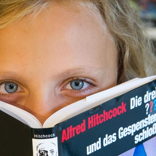 Ein Kind mit einem Buch aus der Reihe "Die drei ???"