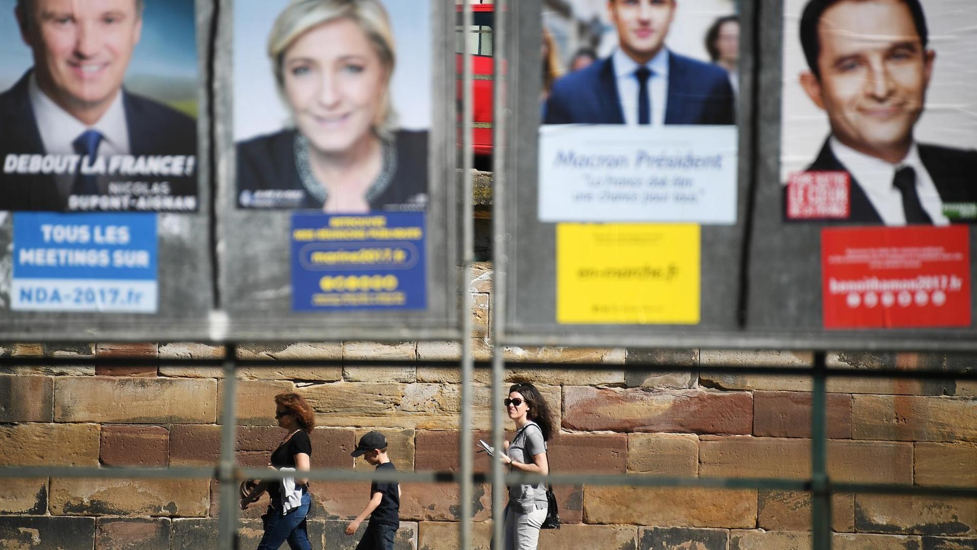3 junge Leute spazieren unterhalb einer riesigen Plakatwand mit den Kandidaten der französischen Präsidentschaftswahlen am 10.04.2017, in Straßburg. 3 junge Leute spazieren unterhalb einer riesigen Plakatwand mit den Kandidaten der französischen Präsidentschaftswahlen am 10.04.2017, in Straßburg.