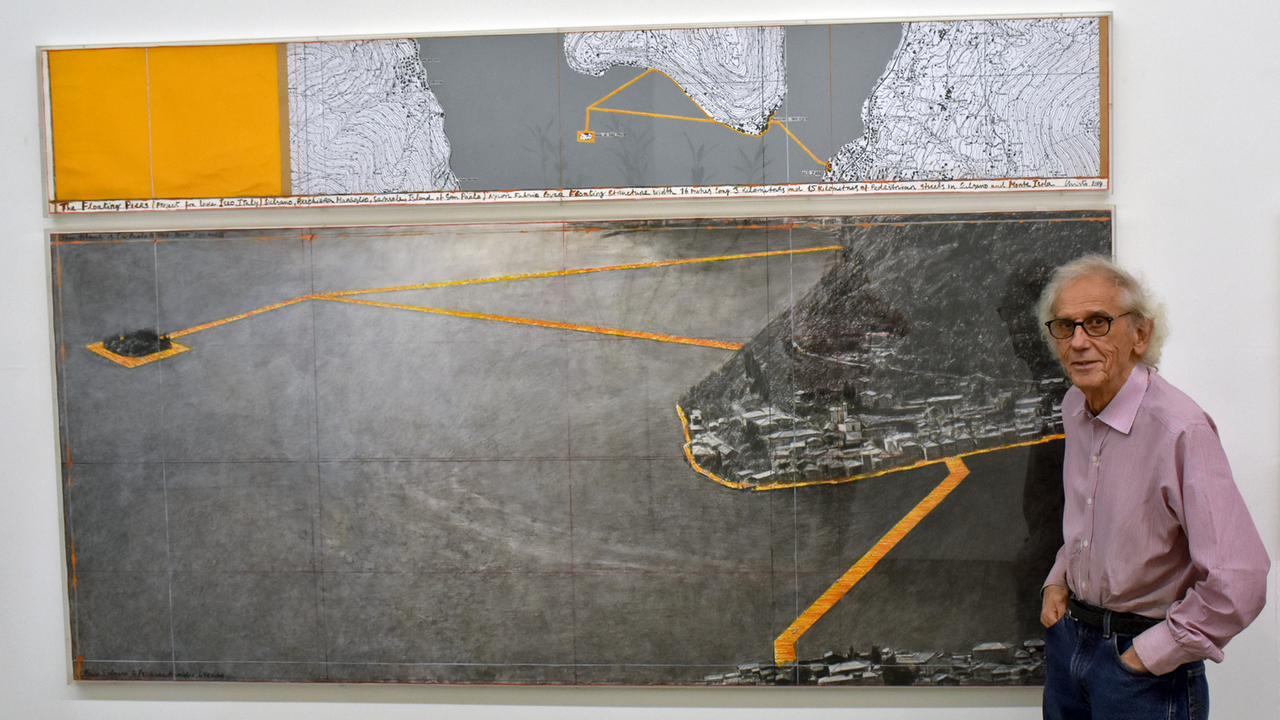 Christo in seinem Atelier in New York: Er steht vor einem Bild, das sein Projekt "Floating Piers" zeigt. Der Künstler möchte schwimmende Stege bauen, die er mit knallgelben Stoff beziehen möchte. 
