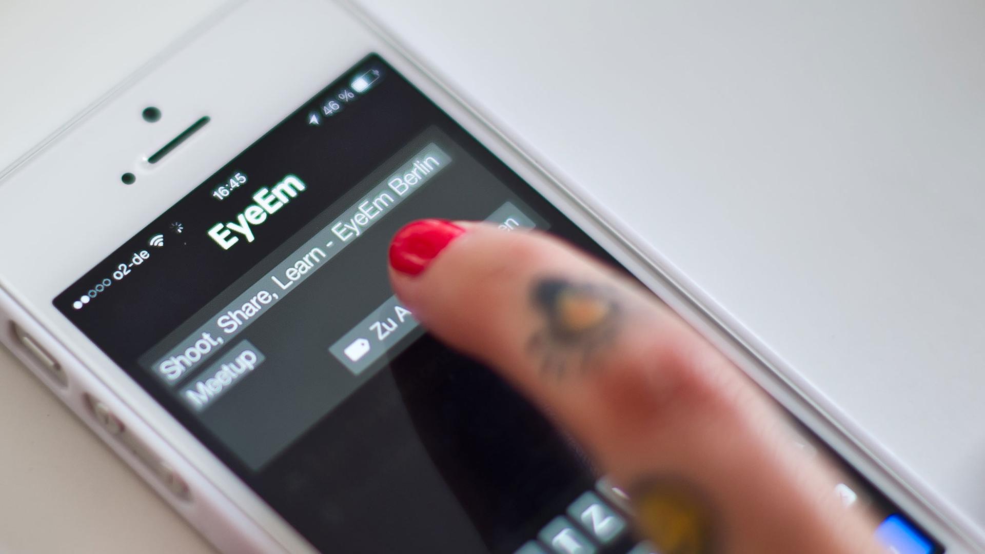 Eine Frau lädt während mit ihrem Smartphone ein Foto hoch. Eine Frau lädt während mit ihrem Smartphone ein Foto hoch.