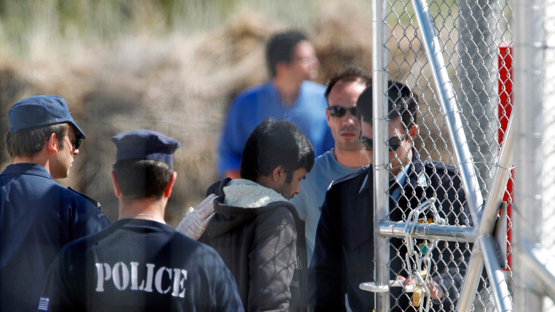 Polizeimänner eskortieren Immigranten zum Einwandererlager in Amygdaleza.