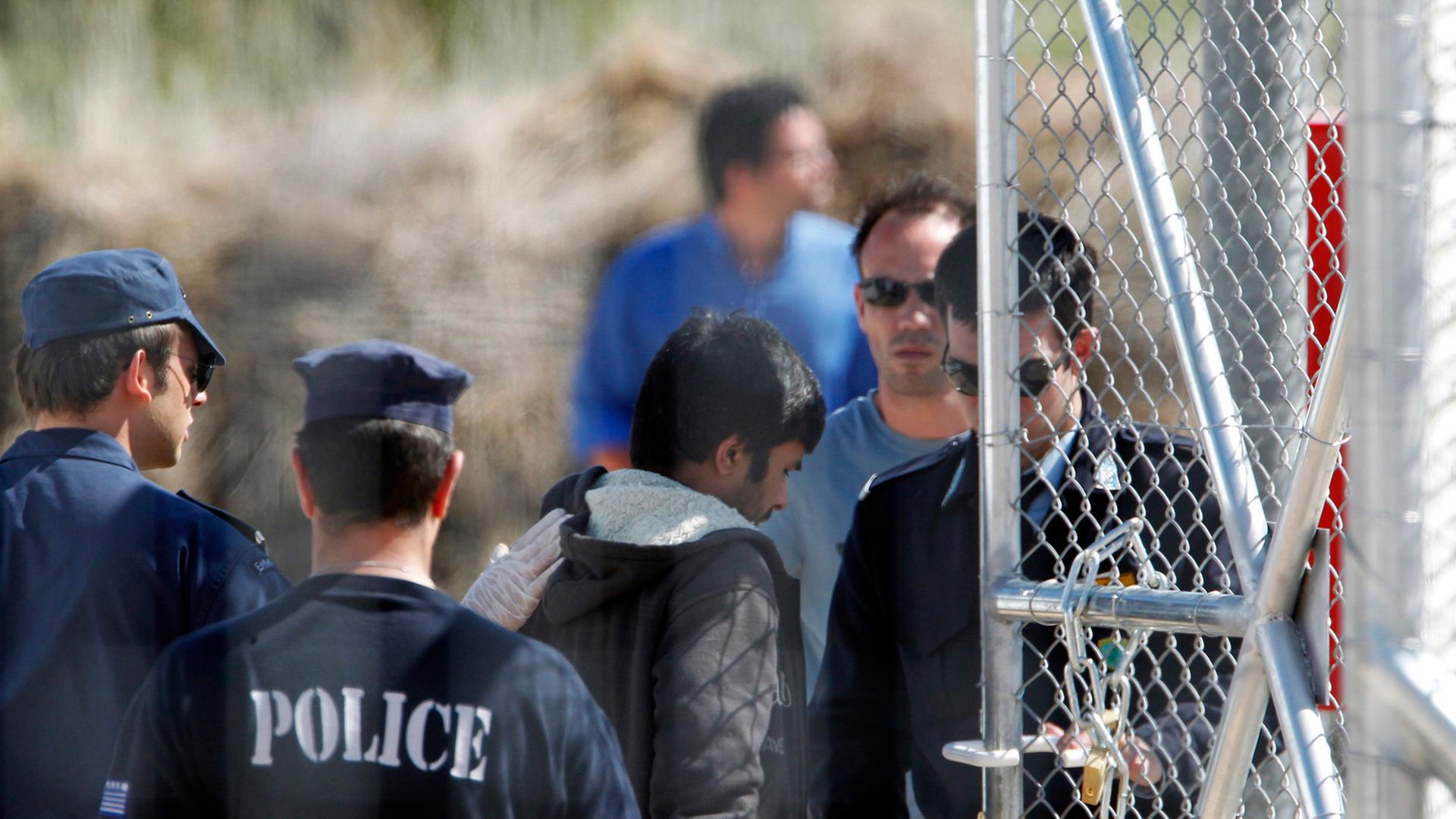 Polizeimänner eskortieren Immigranten zum Einwandererlager in Amygdaleza. Polizeimänner eskortieren Immigranten zum Einwandererlager in Amygdaleza.