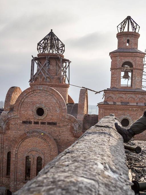 Soldat vor zerstörter Kirche im ukrainischen Dorf Pisky.