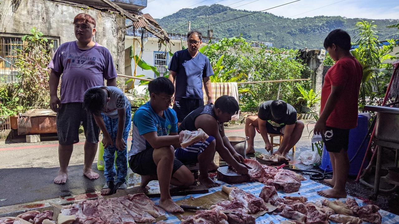 Eine Gruppe zerteilt auf der Straße ein Schwein. Eine Gruppe zerteilt auf der Straße ein Schwein.