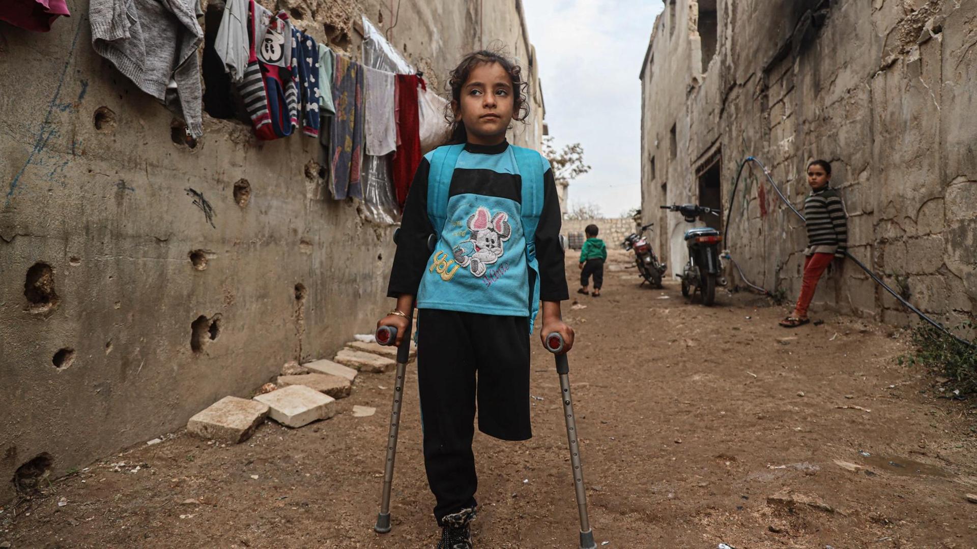 Die neunjährige Fatima Ahmad Mostafa, steht auf einem Bein und einer Krücke in einer Straße in einem Vorort von Idlib in Syrien. Die neunjährige Fatima Ahmad Mostafa, steht auf einem Bein und einer Krücke in einer Straße in einem Vorort von Idlib in Syrien.