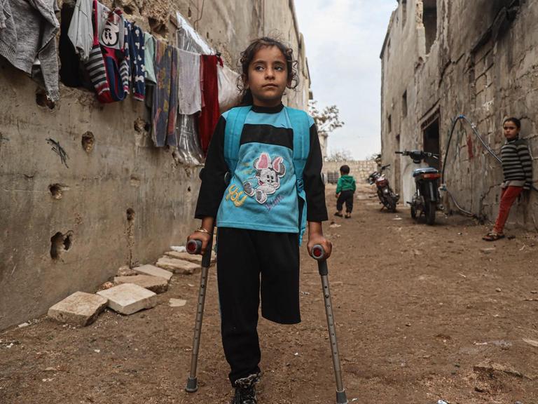 Die neunjährige Fatima Ahmad Mostafa, steht auf einem Bein und einer Krücke in einer Straße in einem Vorort von Idlib in Syrien.