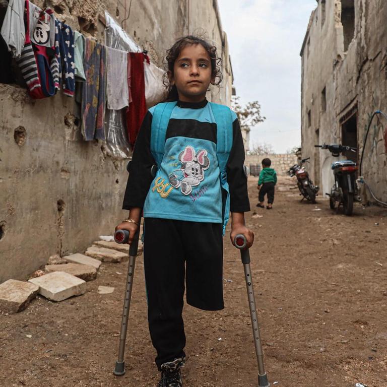 Die neunjährige Fatima Ahmad Mostafa, steht auf einem Bein und einer Krücke in einer Straße in einem Vorort von Idlib in Syrien. 