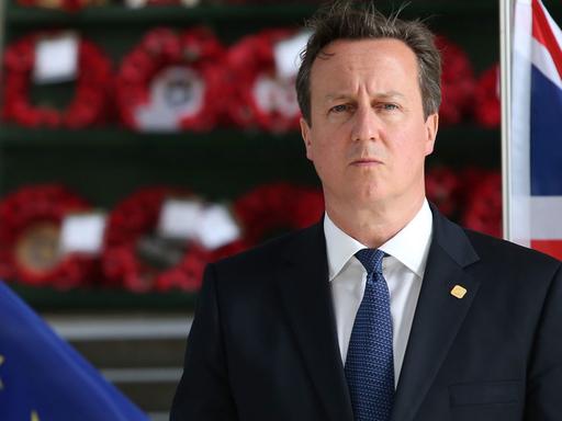 David Cameron zwischen den Flaggen Großbritanniens und der EU.