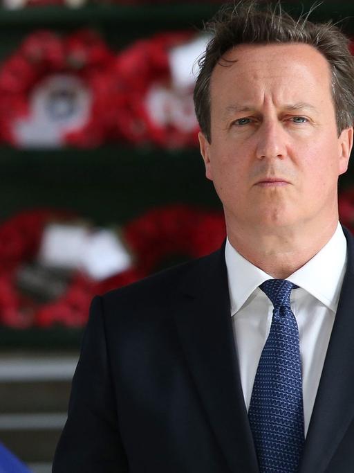 David Cameron zwischen den Flaggen Großbritanniens und der EU.