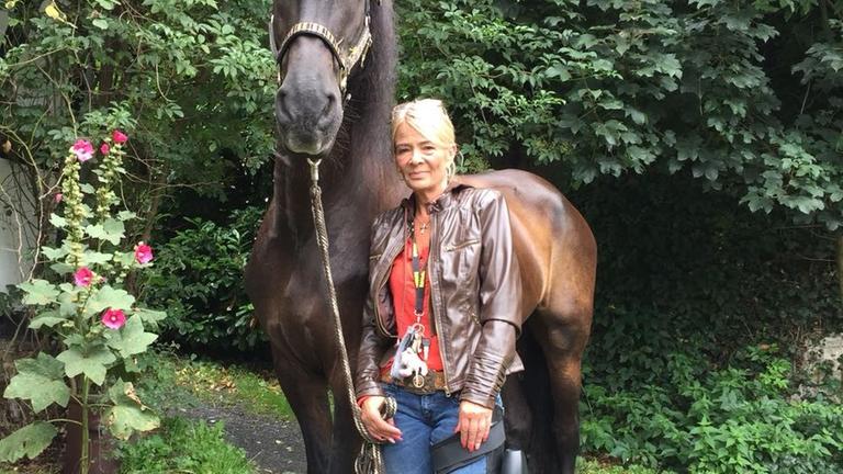 Birgit Strässer trägt eine Bein-Prothese und steht neben ihrem Pferd Birgit Strässer trägt eine Bein-Prothese und steht neben ihrem Pferd