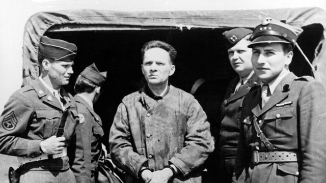 Der Kommandant des Konzentrationslagers Auschwitz, Rudolf Höss (Mitte), steht Mitte der 40er-Jahre auf dem Flugplatz in Nürnberg. Er wird zusammen mit einer Gruppe Offiziere nach Polen ausgeliefert.