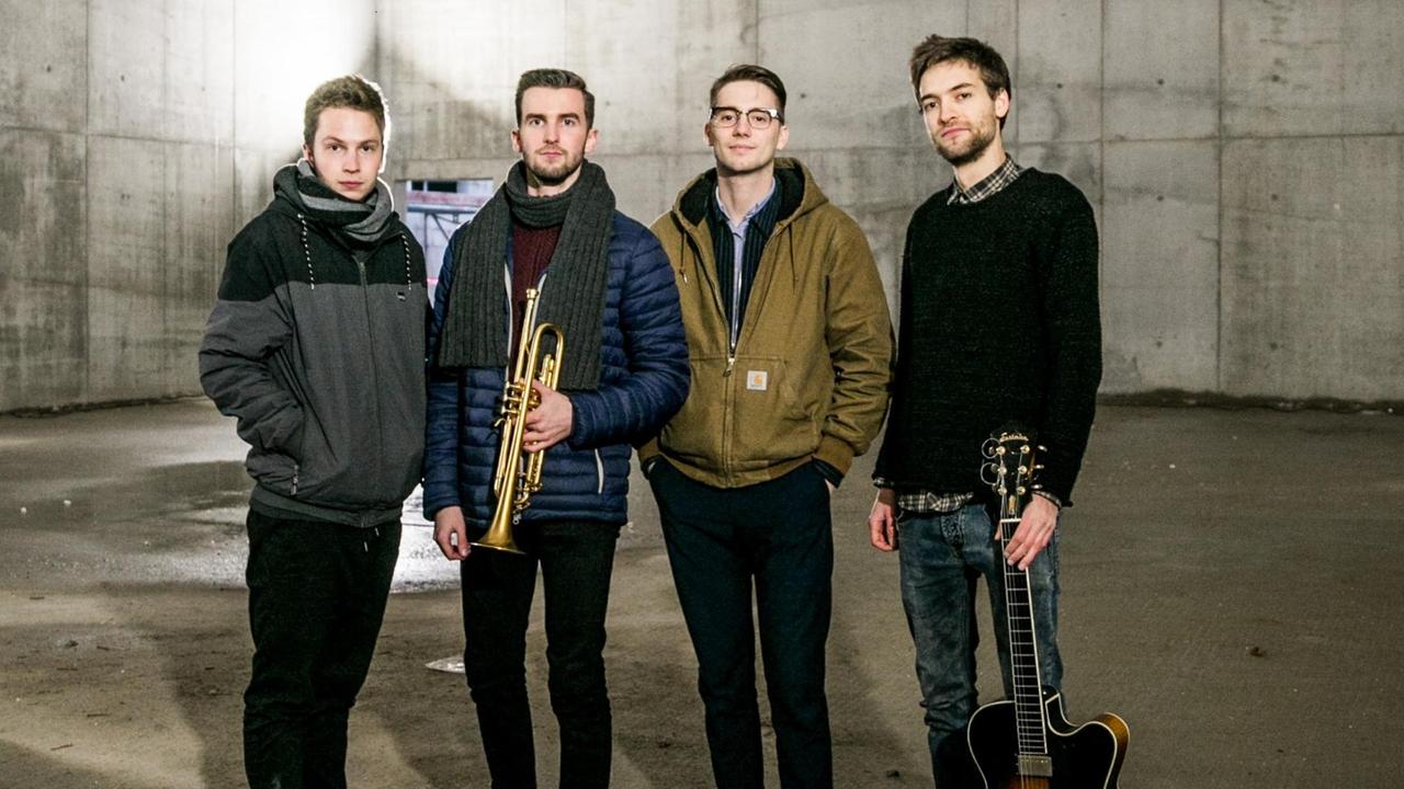 Vier Musiker stehen in einer Baustelle vor einer Stahlbetonwand Vier Musiker stehen in einer Baustelle vor einer Stahlbetonwand