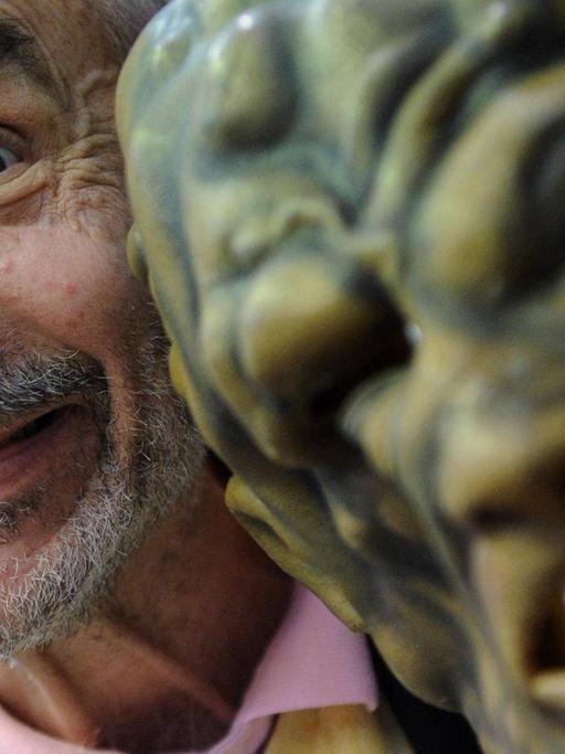 Regisseur und Produzent Lloyd Kaufman schaut hinter einer Gruselmaske hervor.
