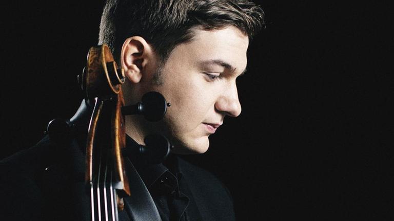 Der Cellist steht seitlich zur Kamera und hält sein Instrument im Arm. Der Cellist steht seitlich zur Kamera und hält sein Instrument im Arm.