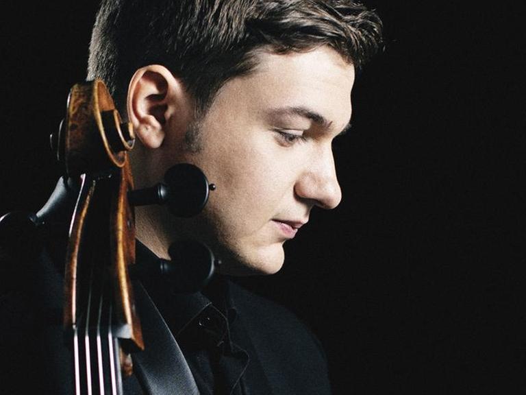 Der Cellist steht seitlich zur Kamera und hält sein Instrument im Arm.