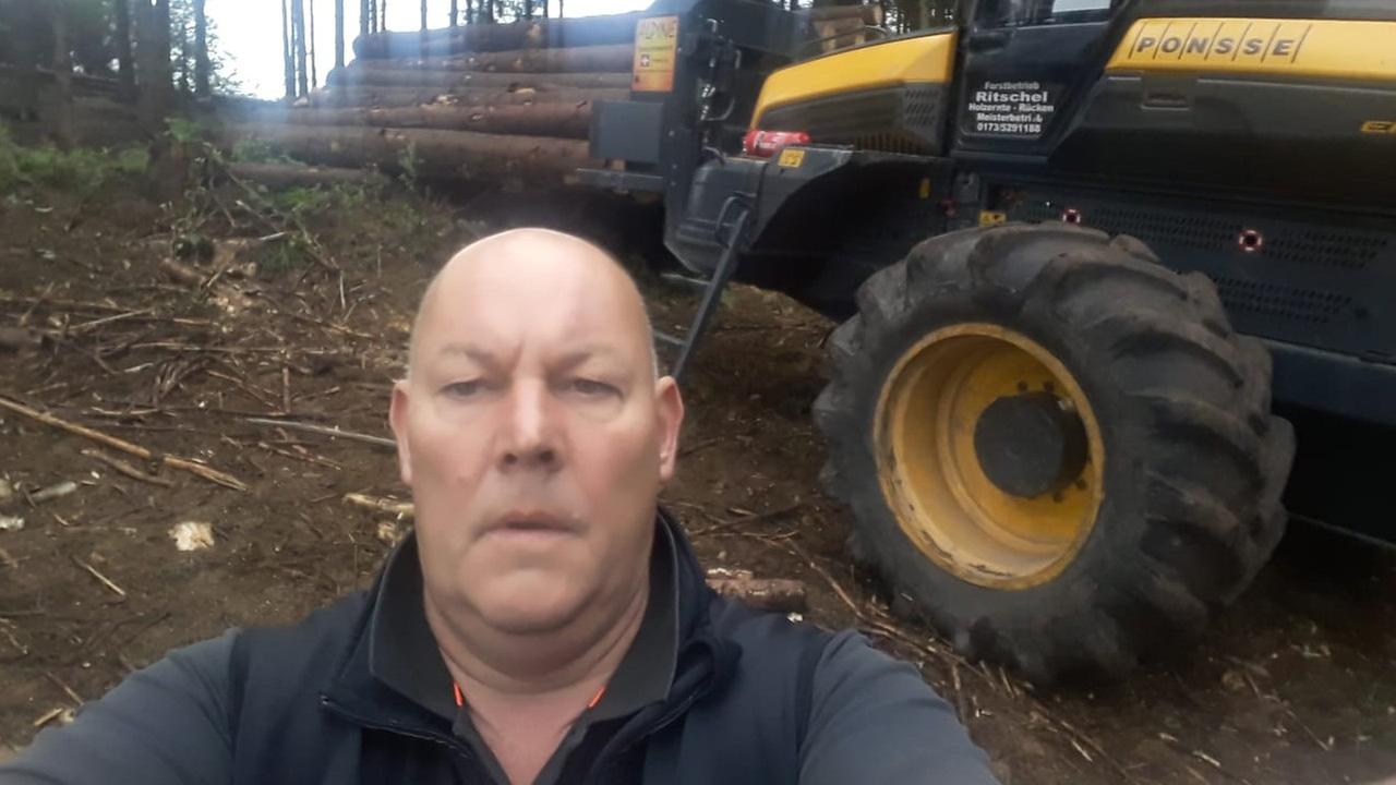 Thomas Ritschelvom gleichnahmigen Forstbetrieb in typischer Selfie-Pose im Wald. Im Hintergrund ein Harvester für die Holzernte und gefällte Baumstämme. Thomas Ritschelvom gleichnahmigen Forstbetrieb in typischer Selfie-Pose im Wald. Im Hintergrund ein Harvester für die Holzernte und gefällte Baumstämme.