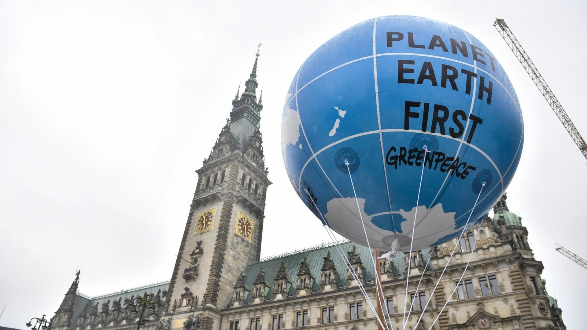 Ein Ballon mit der Aufschrift "Planet Earth First" hängt vor dem Hamburger Rathaus.