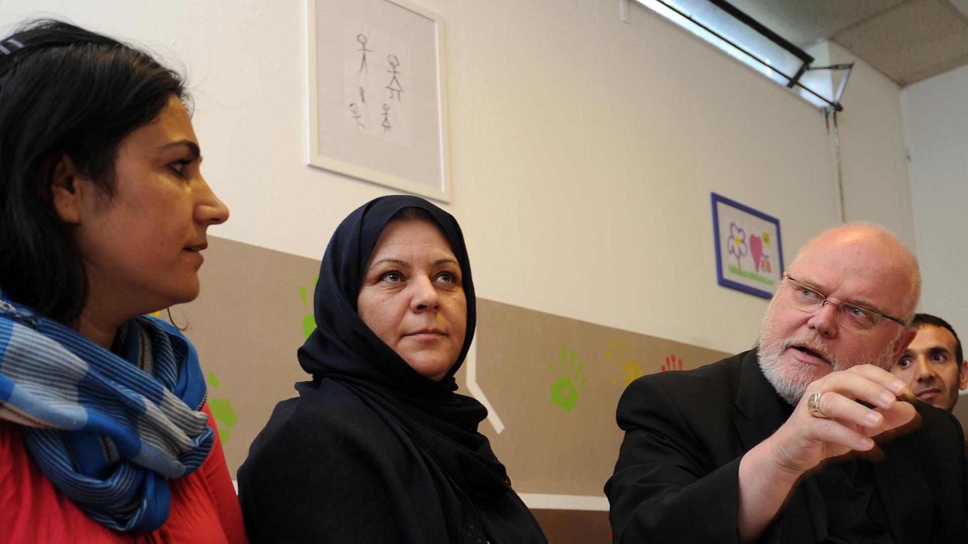 Der Münchner Erzbischof, Kardinal Reinhard Marx (rechts), spricht am 18.07.2014 in München (Bayern) mit Flüchtlingen in einem Gemeinschaftsraum eines Flüchtlingsheims. Der Münchner Erzbischof, Kardinal Reinhard Marx (rechts), spricht am 18.07.2014 in München (Bayern) mit Flüchtlingen in einem Gemeinschaftsraum eines Flüchtlingsheims.