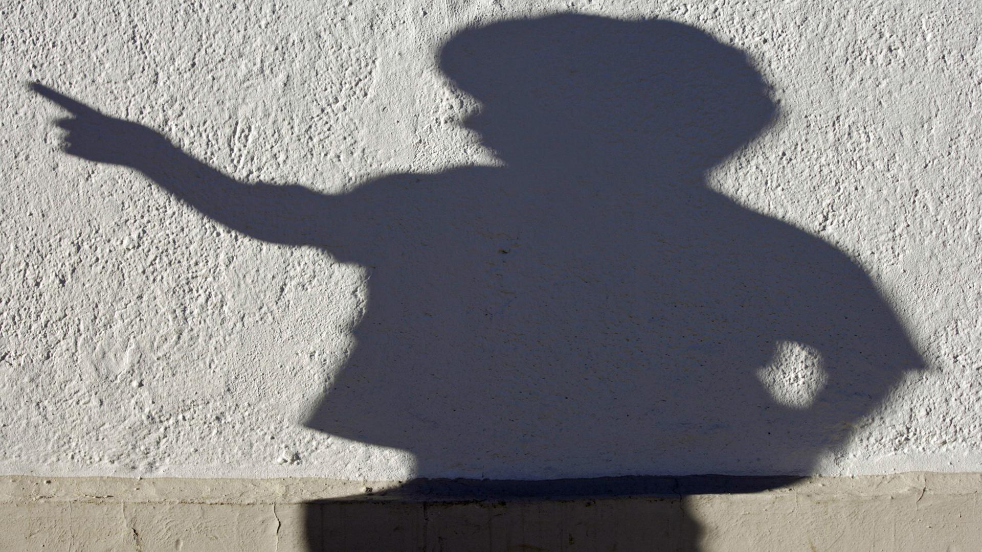 Der Schatten einer Kind-Skulptur an einer Hauswand Der Schatten einer Kind-Skulptur an einer Hauswand