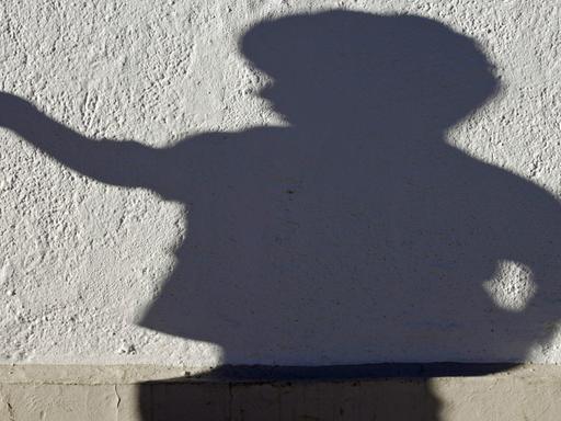 Der Schatten einer Kind-Skulptur an einer Hauswand