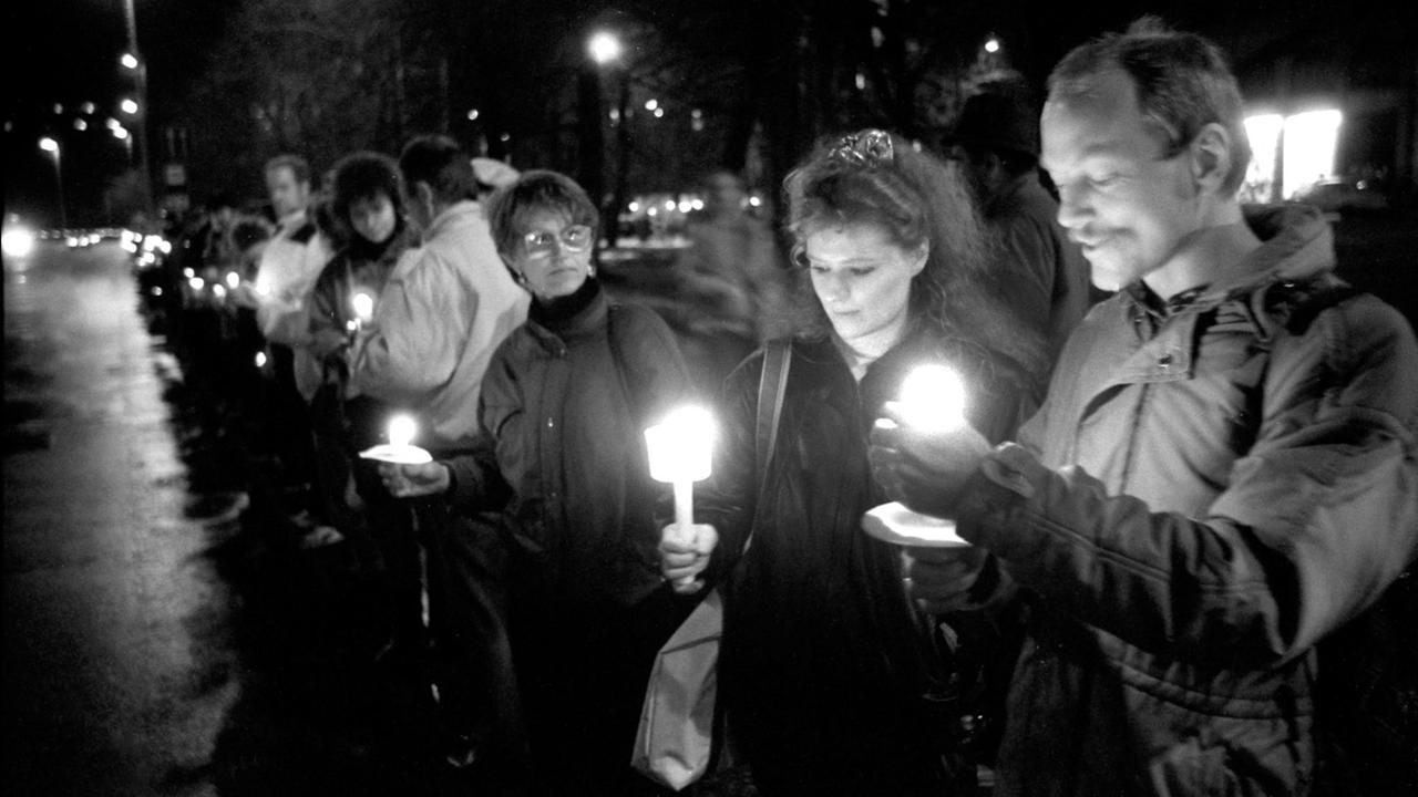 Eine historische schwarz/weiss Aufnahme von der letzten Montagsdemo in Leipzig 1989. Die Menschen stehen mit Kerzen in den Händen in einer Gruppe zusammen. Eine historische schwarz/weiss Aufnahme von der letzten Montagsdemo in Leipzig 1989. Die Menschen stehen mit Kerzen in den Händen in einer Gruppe zusammen.