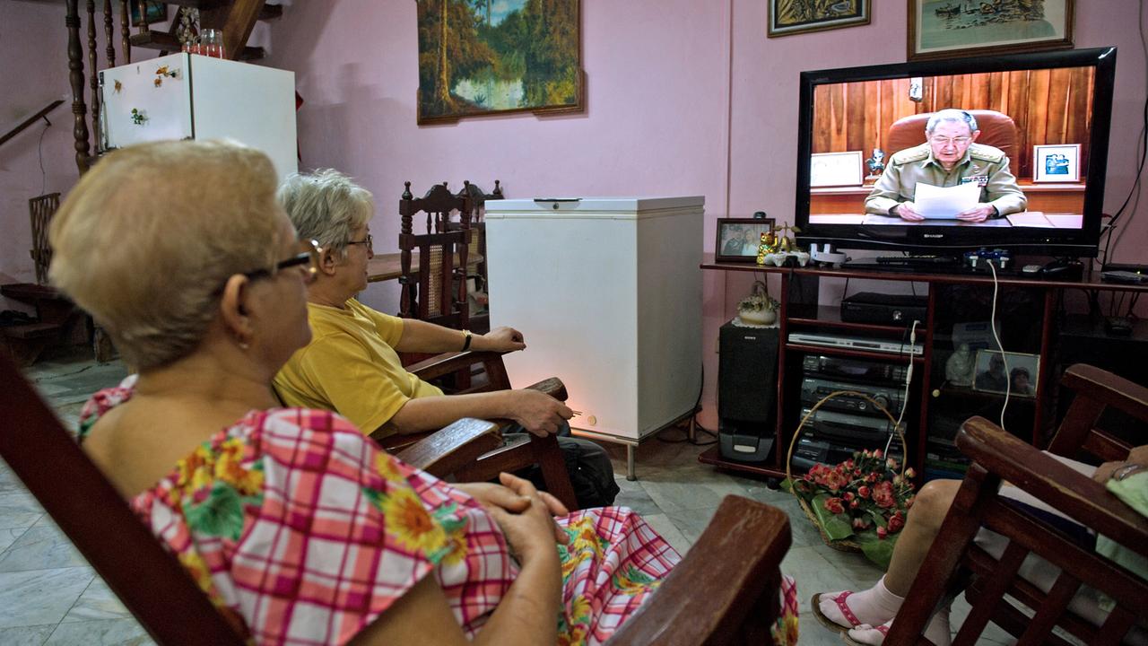 Mehrere kubanische Frauen sitzen vor dem Fernseher, in dem Staatspräsident Raúl Castro bei einer Ansprache zu sehen ist.