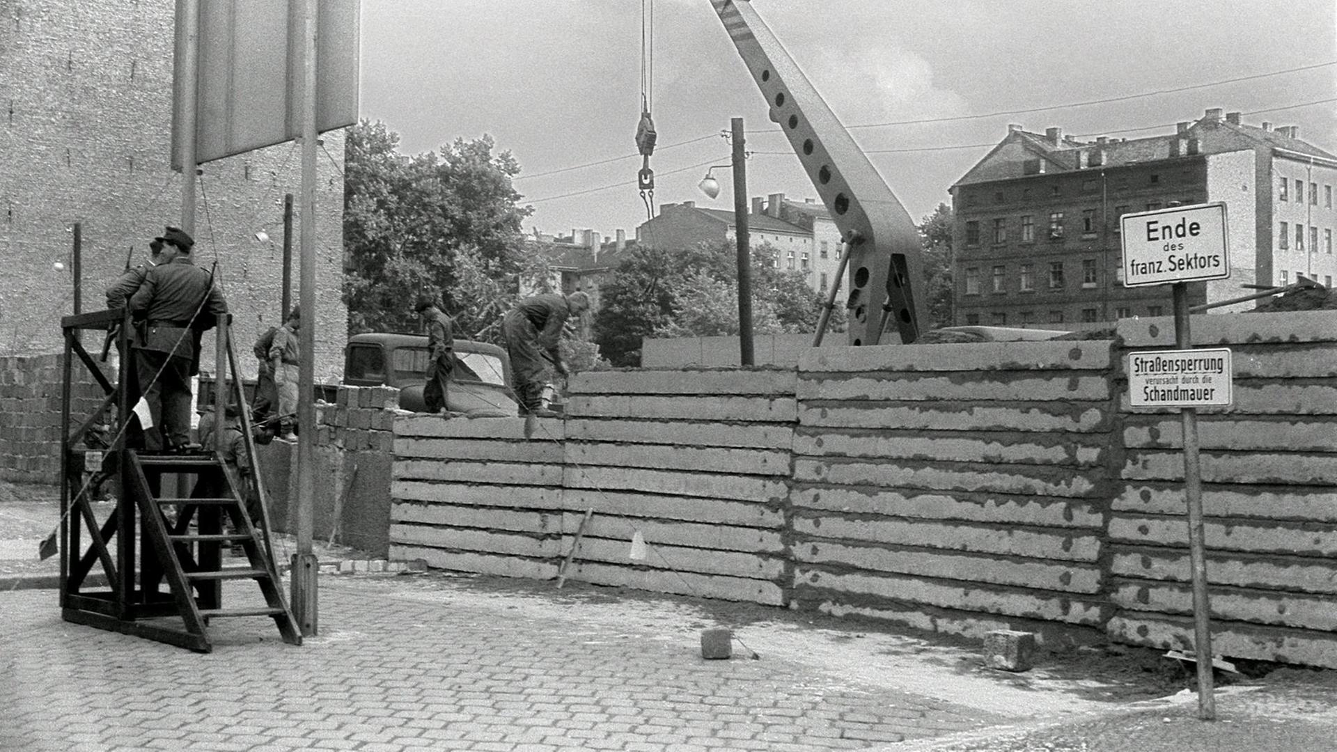 Unter der Aufsicht von bewaffneten Volkspolizisten errichtet eine Ostberliner Maurerkolonne am 18.8.1961 an der sowjetisch-amerikanischen Sektorengenze am Potsdamer Platz eine mannshohe Mauer. Unter der Aufsicht von bewaffneten Volkspolizisten errichtet eine Ostberliner Maurerkolonne am 18.8.1961 an der sowjetisch-amerikanischen Sektorengenze am Potsdamer Platz eine mannshohe Mauer.