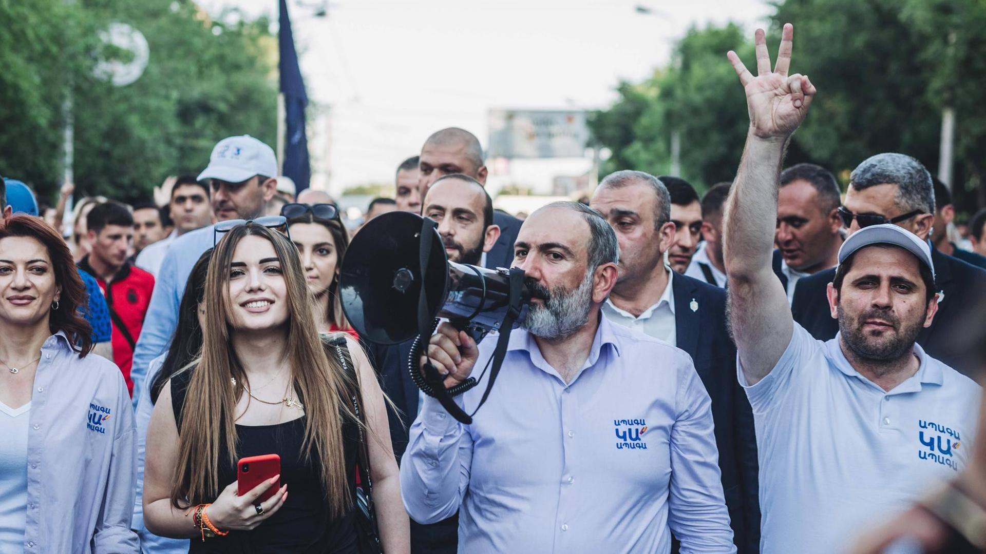 Nikol Pashinyan spricht in ein Megafon, umringt von seinen Anhänger*innen Nikol Pashinyan spricht in ein Megafon, umringt von seinen Anhänger*innen