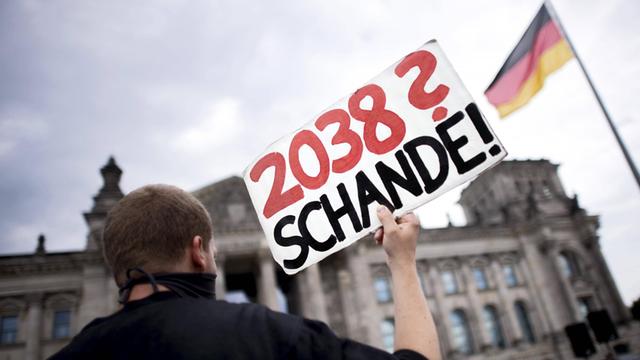 Ein Aktivist mit Schild "2038? Schande!" protestiert gegen das Kohleausstiegsgesetz.