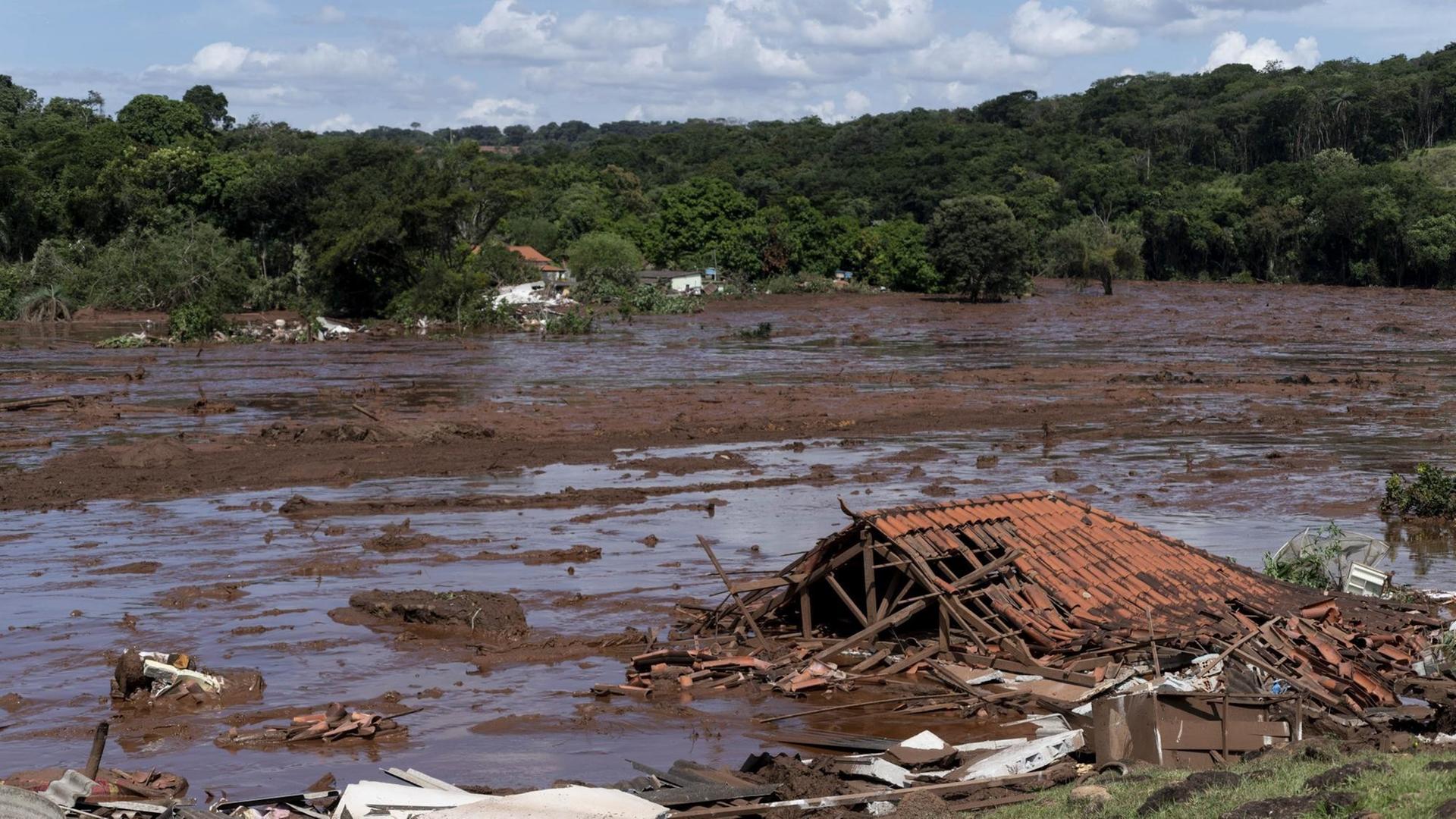 Das Foto zeigt eine braune Schlammflut und Trümmer eines Gebäudes nach einem Dammbruch in Brasilien. Das Foto zeigt eine braune Schlammflut und Trümmer eines Gebäudes nach einem Dammbruch in Brasilien.