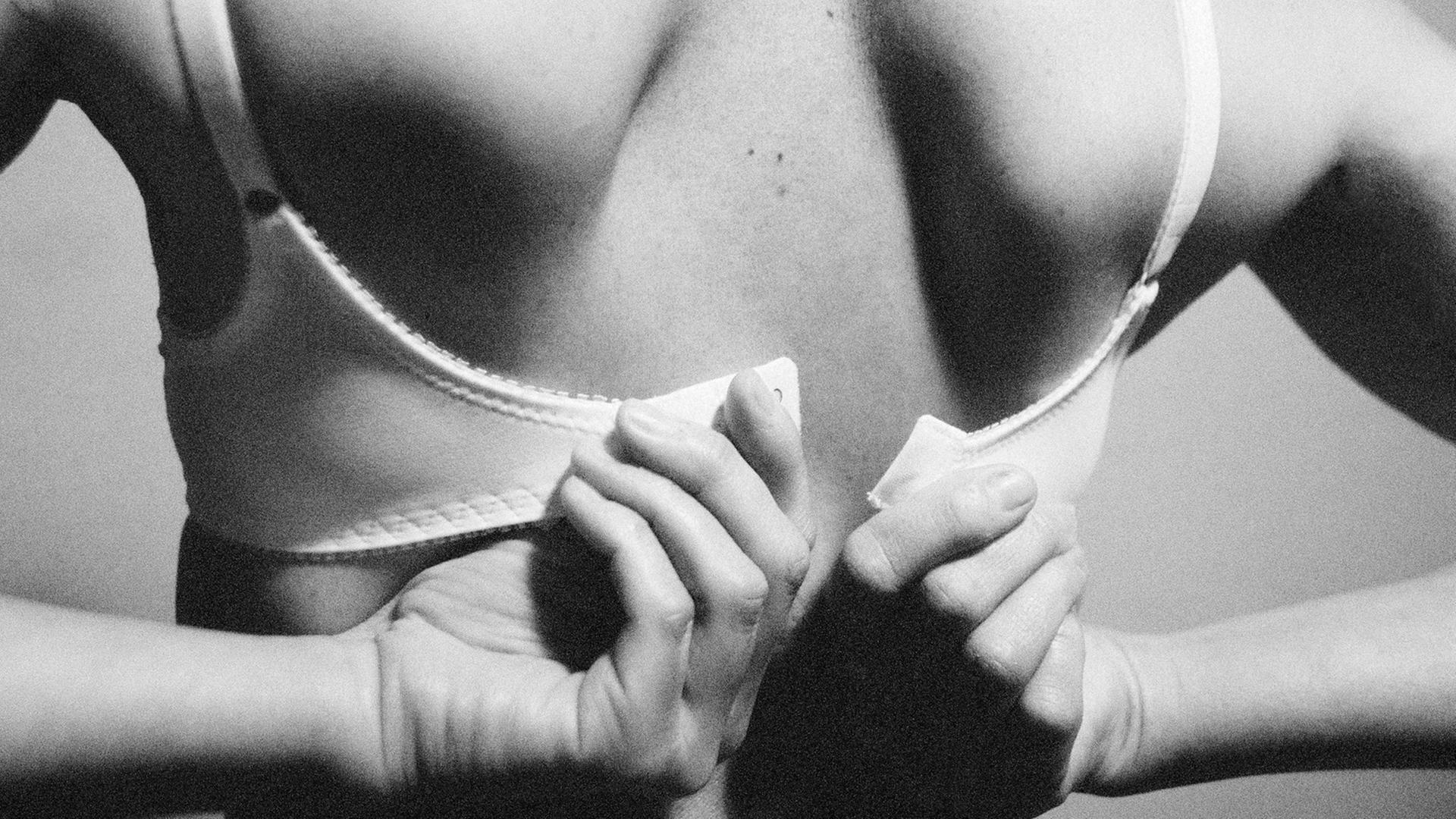 Eine Frau bindet sich den Büsternhalter zu Eine Frau bindet sich den Büsternhalter zu