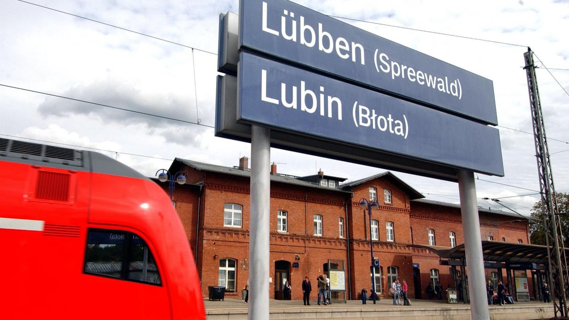 Ein Regionalzug fährt in den Bahnhof der brandenburgischen Stadt Lübben ein. Der Ortsname auf den Bahnhofsschildern ist auch in sorbischer Sprache dargestellt.