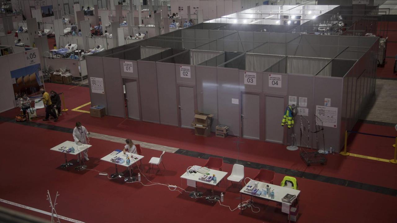 In einer Messehalle sind aus grauen dünnen Wänden einzelne Quadrate abgeteilt, vorne stehe vier Tische zur Anmeldung. In einer Messehalle sind aus grauen dünnen Wänden einzelne Quadrate abgeteilt, vorne stehe vier Tische zur Anmeldung.