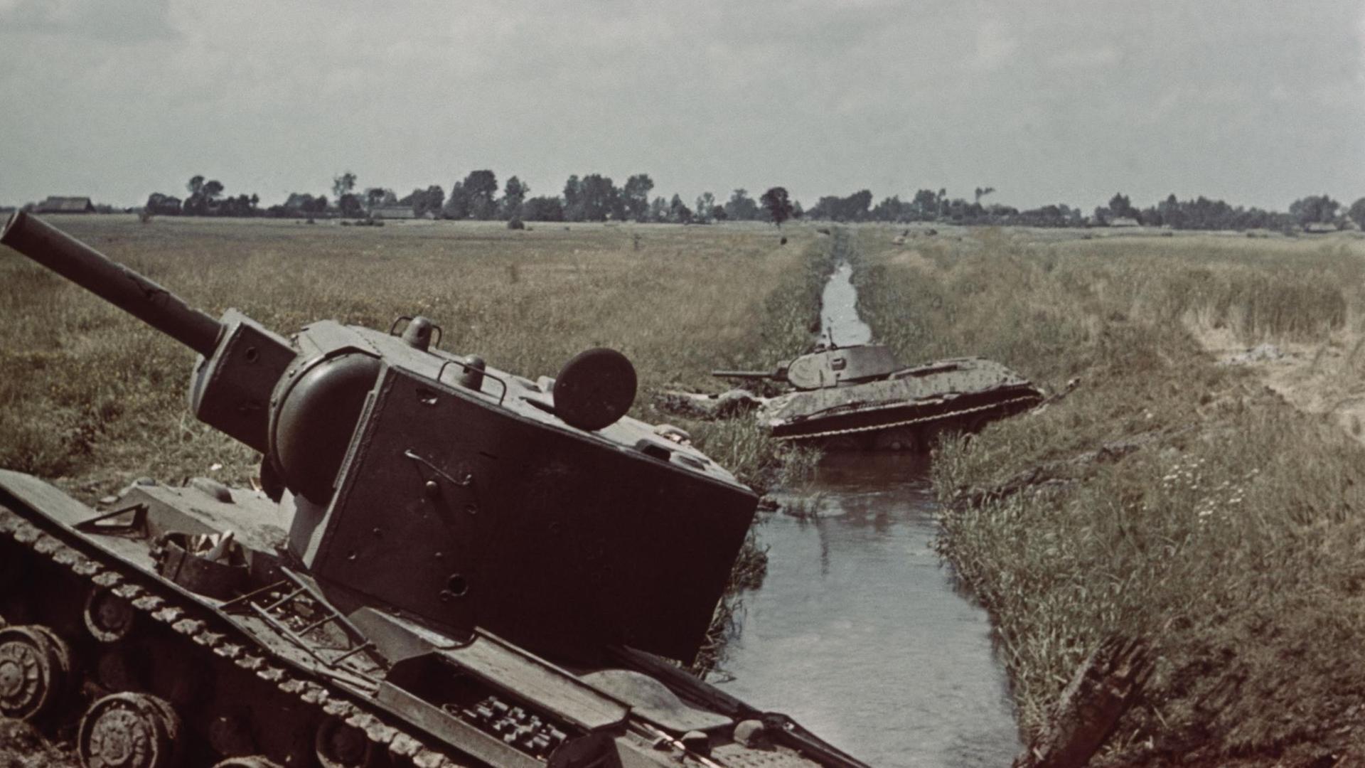 Ein historisches Farbfoto zeigt die Trümmer zweier Panzer an der Böschung eines Kanals