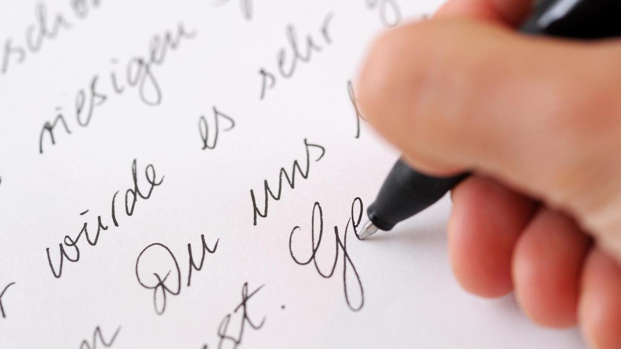 Eine Frau schreibt einen Brief mit einem Kugelschreiber.